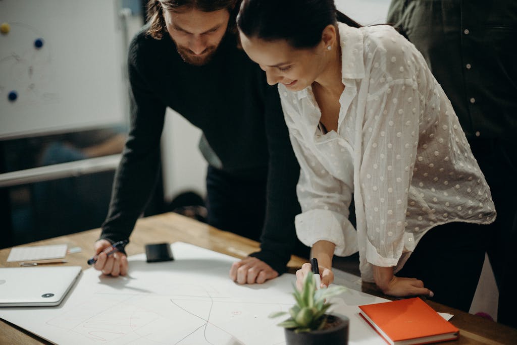 Two colleagues engage in a creative brainstorming session at the office, working together on new ideas.